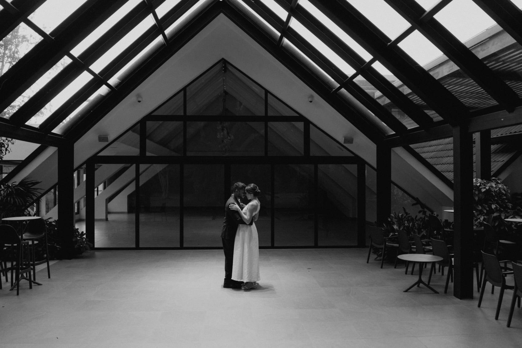 Mafe y Rafa abrazados en el salón acristalado, en blanco y negro
